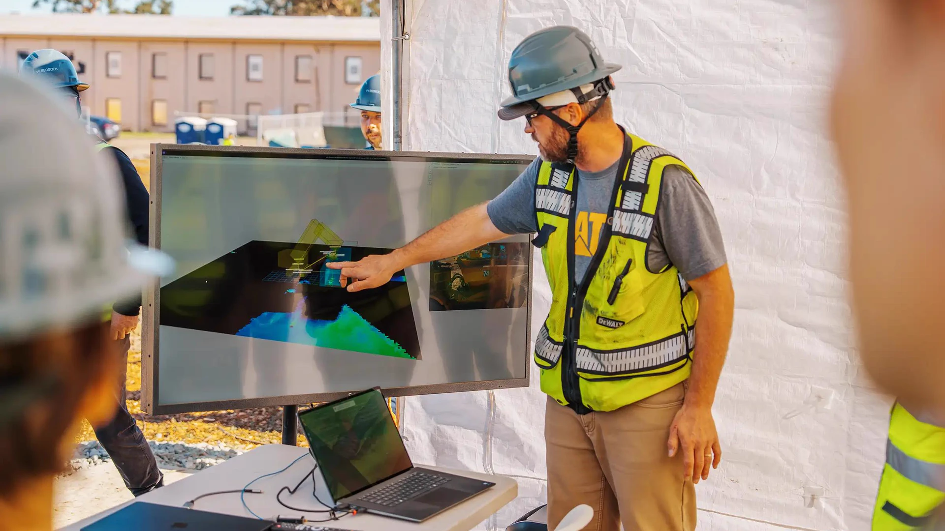 Bedrock Robotics crew member reviewing an excavator autonomy visualization at a construction site